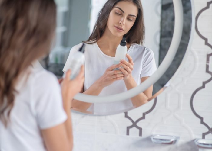 Checking the content. A woman reading a label on hairspray bottle
